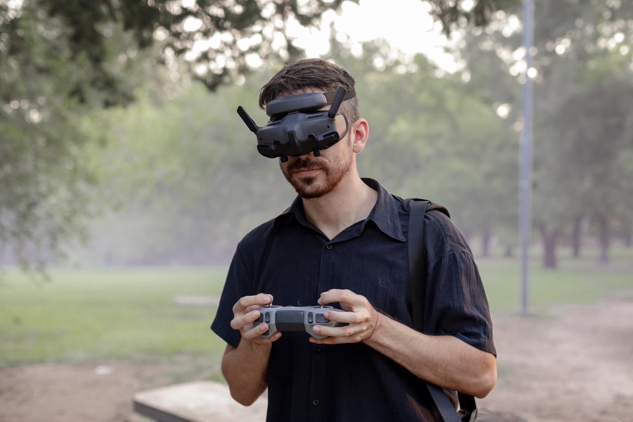 Facundo Álvarez wearing FPV goggles, holding a DJI controller in a park
